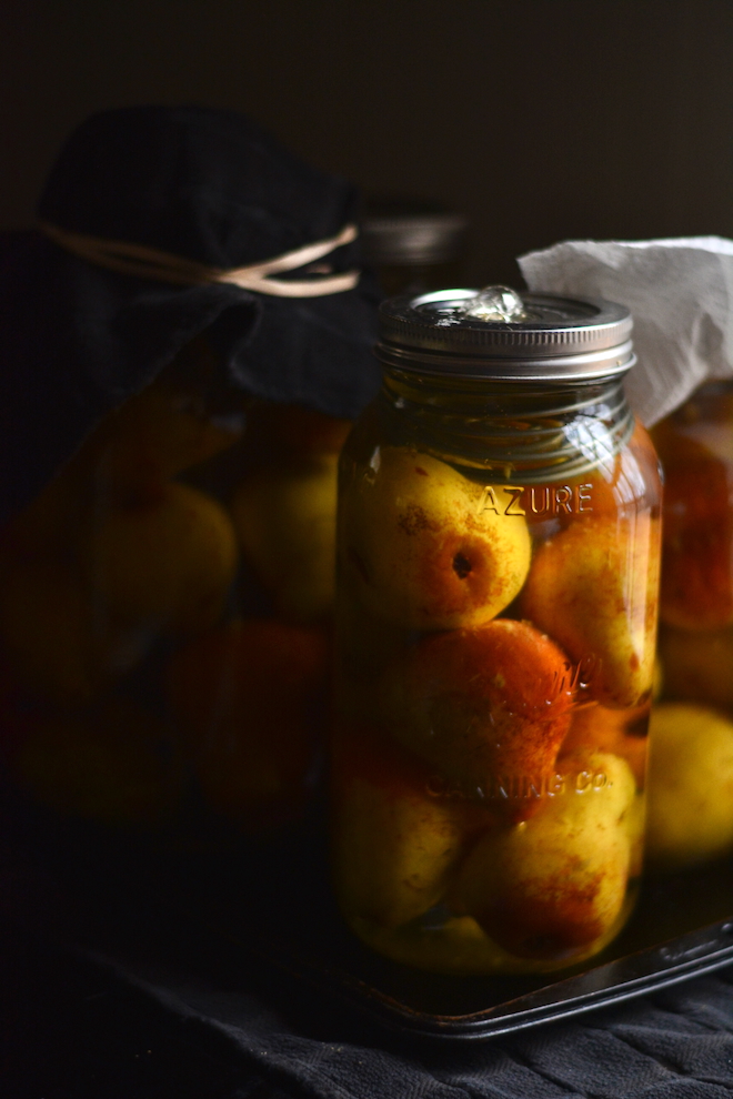 fermented whole pears in jars fermenting on a tray