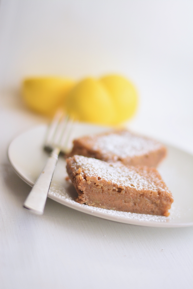 fresh squeezed lemons with lemon bars made with fresh flour and dusted with confectioners sugar