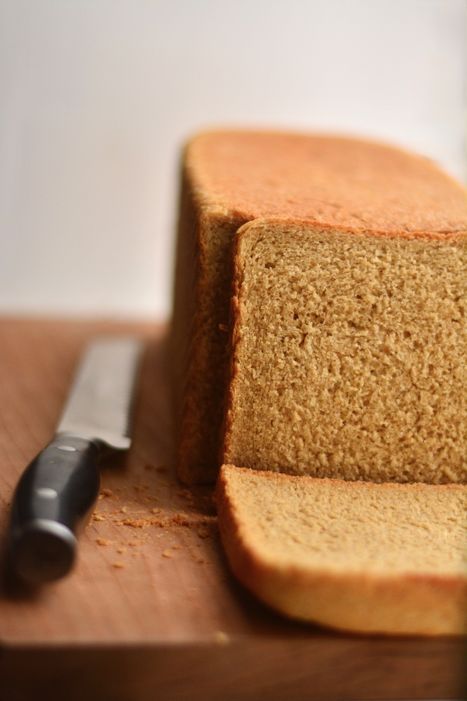 homemade sandwich bread made with fresh milled flour on a cutting board with a bread knife