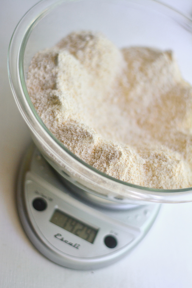fresh milled flour is it worth it? Let's figure out the cost of this big bowl of fresh milled flour getting weighed on a kitchen scale.
