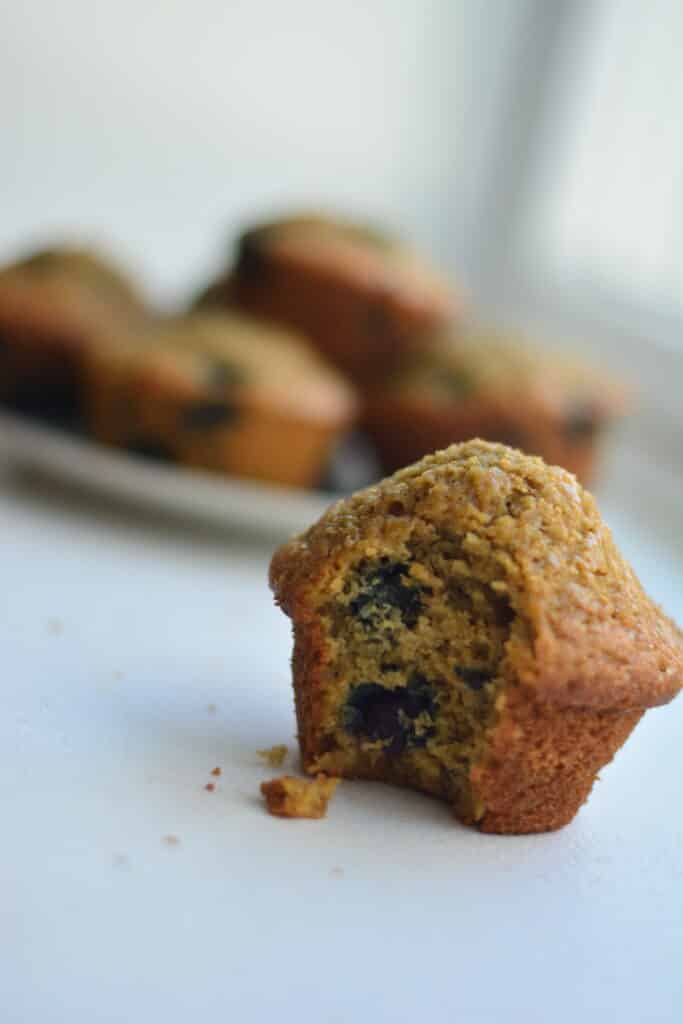 homemade blueberry muffin with fresh flour, with a plate of blueberry muffins in background