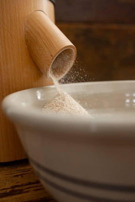 fresh milled flour coming out of a grain mill, whole wheat flour in a bowl