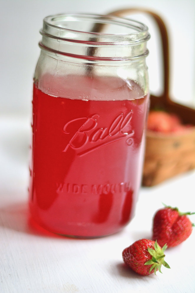 homemade strawberry syrup in mason jar with basket and berries