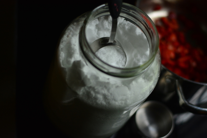 gallon jar of white fine sugar, allulose, with measuring cup