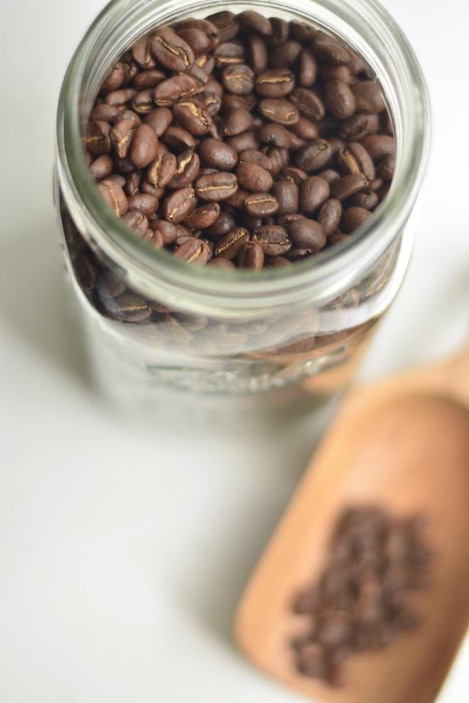 mason jar filled with coffee beans and a wooden scoop in the background