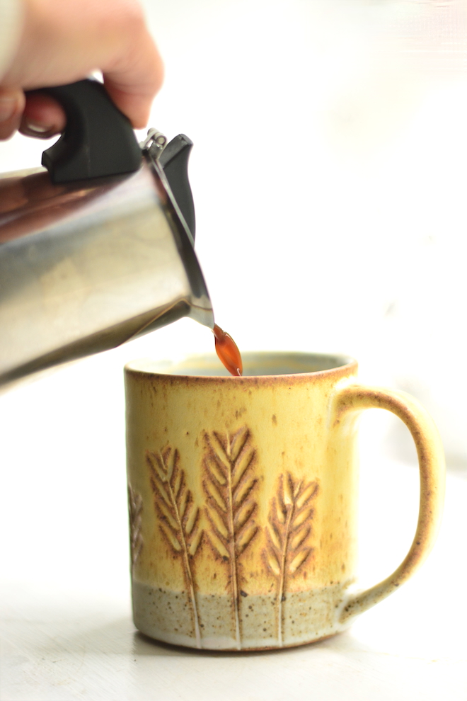 hot latte made with moka pot espresso, moka pot pouring espresso in a mug