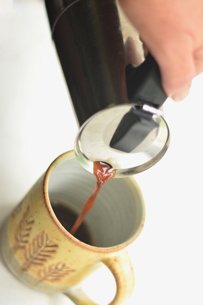 pouring espresso into a buttercream yellow pottery mug from a nontoxic moka pot