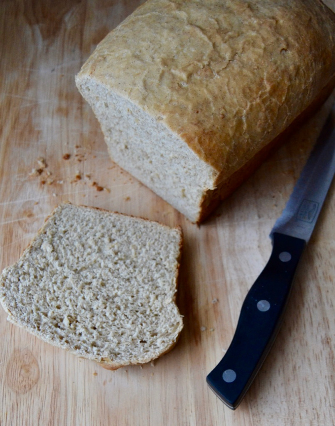 honey oat sandwich bread with fresh milled flour, sliced on a cutting board