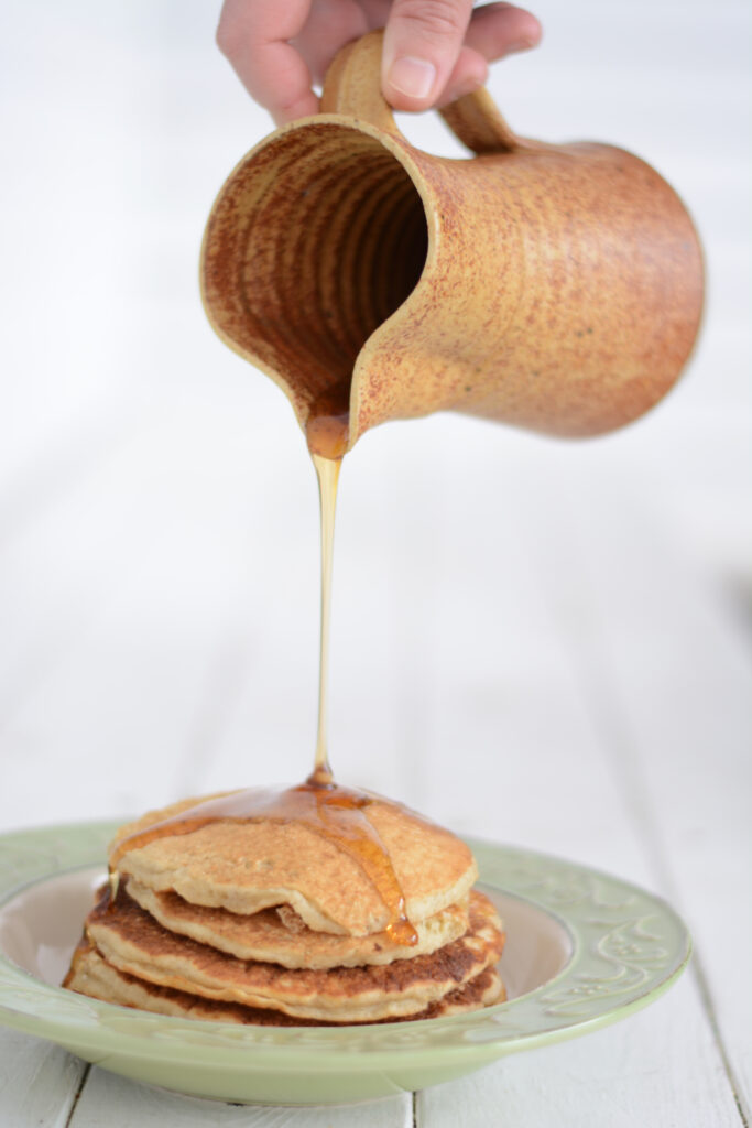 a stack of fresh milled pancakes made with einkorn flour and buckwheat flour with maple syrup poured on top