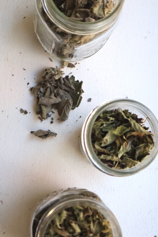 3 glass jars holding herbs on white table