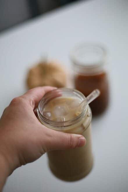 iced pumpkin chai latte in a jar with chai concentrate and a pumpkin in the background