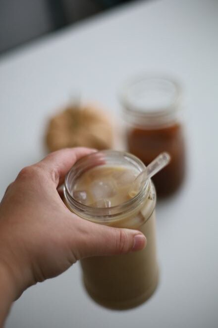 hand holding jar of pumpkin chai latte from concentrate