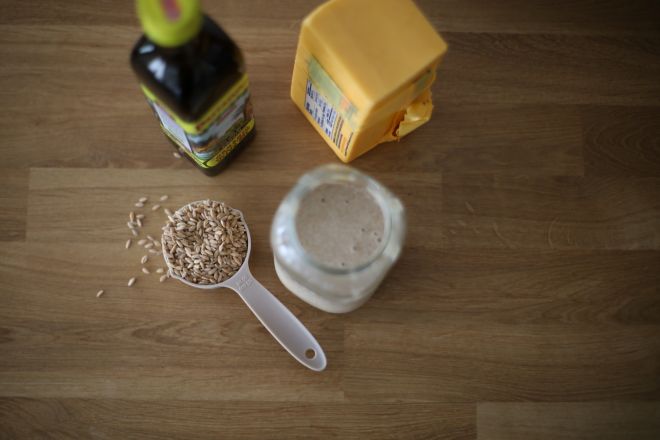 ingredients to make fresh milled sourdough discard crackers, including olive oil, cheddar cheese blog, einkorn wheat berries and a jar of sourdough discard