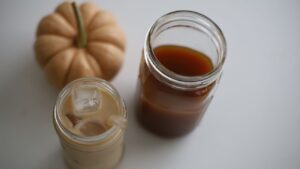 chai latte made from homemade pumpkin chai concentrate with a pumpkin in the background and a jar of chai concentrate