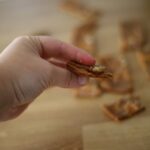 hand holding crispy homemade crackers made with cheddar cheese, sourdough discard and fresh milled einkorn flour with sea salt